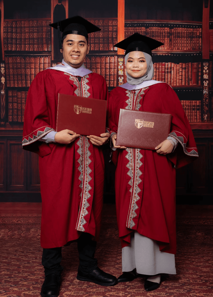 Pasangan graduan berjubah maroon bergambar bersama